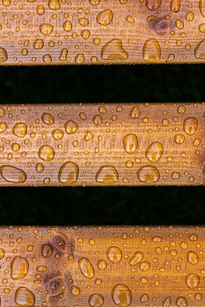 Horizontal background of lacquered burnt wood texture with shiny water drops from the rain wet wooden planks