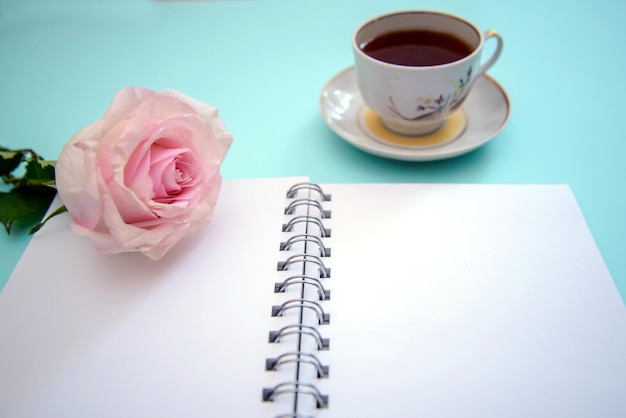 Horizontal background with pink rose, cup of tea and open notepad, with copy space