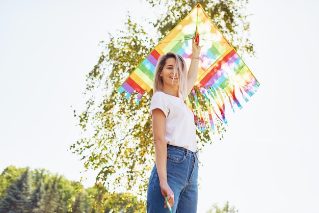 Horizontal bottom view image of a happy young woman smiling and launching a kite on a sunny day Beautiful female playing and have fun outside with a kite in the park