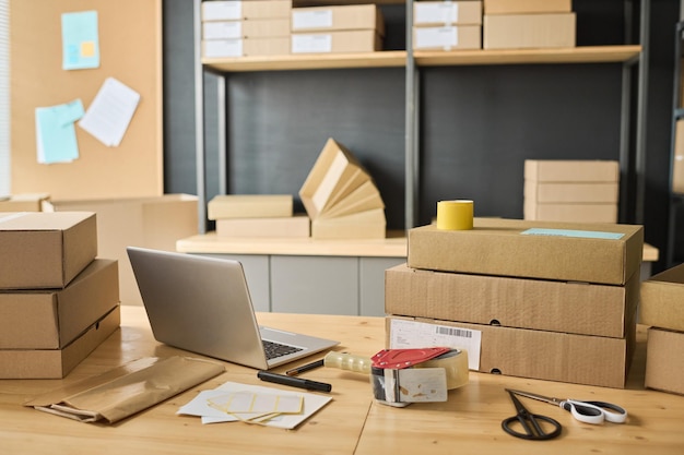 Horizontal image of warehouse with cardboard boxes and laptop on table preparing for future shipping