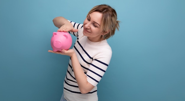 Horizontal photo of attractive young woman in casual outfit cute hugging a piggy bank of coins on a