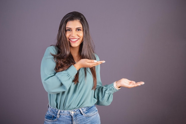 Horizontal photo Beautiful Brazilian woman with casual clothes Jeans and green shirt displaying advertising on the right