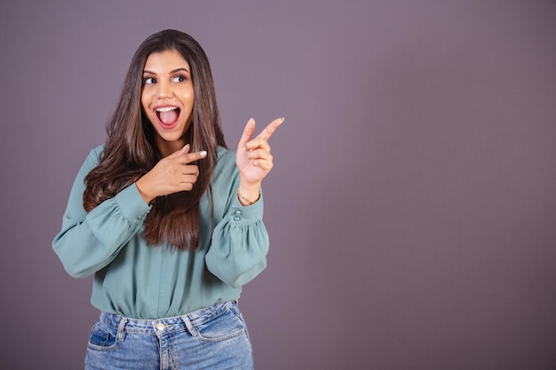 Horizontal photo Beautiful Brazilian woman with casual clothes Jeans and green shirt displaying advertising on the right