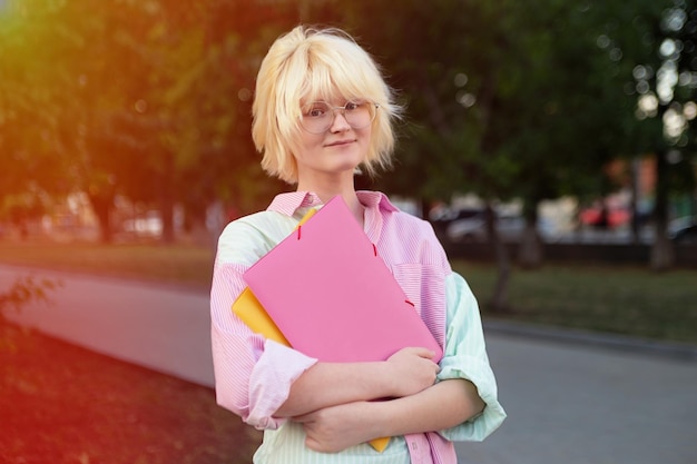 Horizontal photography of teenage girl student staying outsidesunlight on background