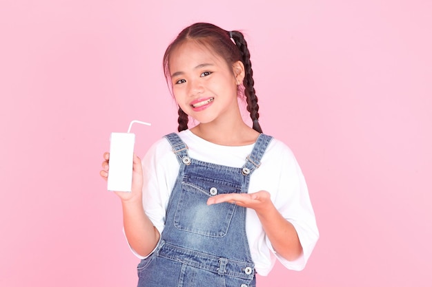 Horizontal portrait of a cute beautiful Asian little kid girl holding milk box isolated on background