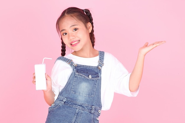 Horizontal portrait of a cute beautiful Asian little kid girl holding milk box isolated on background