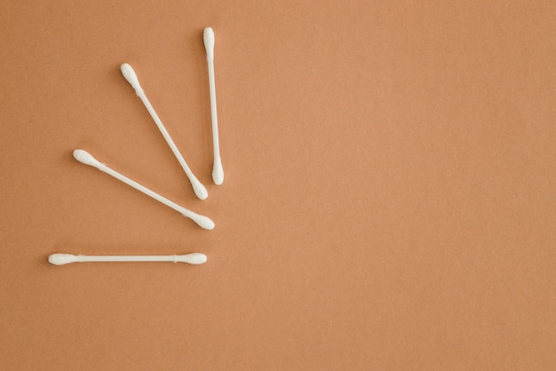 Horizontal rows of cotton swabs on beige background top view