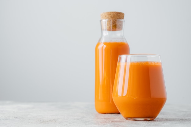 Horizontal shot of fresh carrot juice in glass containers, rich with vitamins