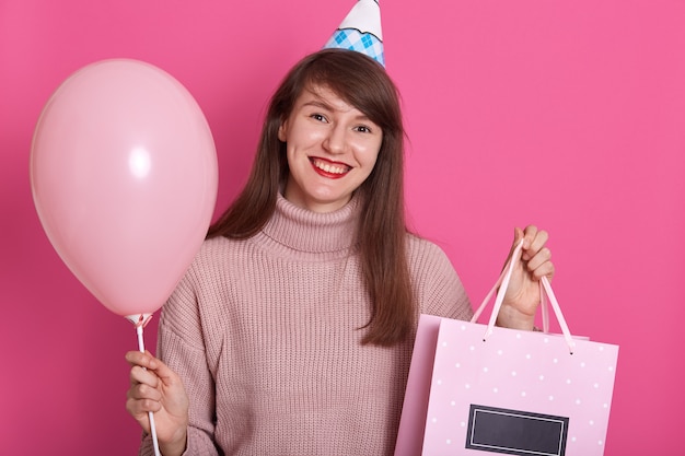 Horizontal shot of teenage girl holding birthday present and balloon