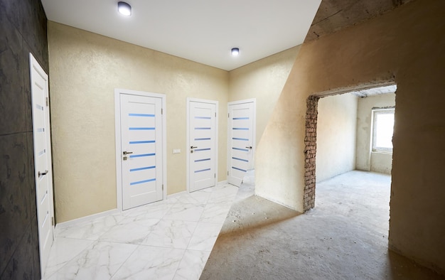 Horizontal snapshot of a room in a big apartment before and after versions modernized corridor with many closed white doors spot lights on the ceiling in a light hallway