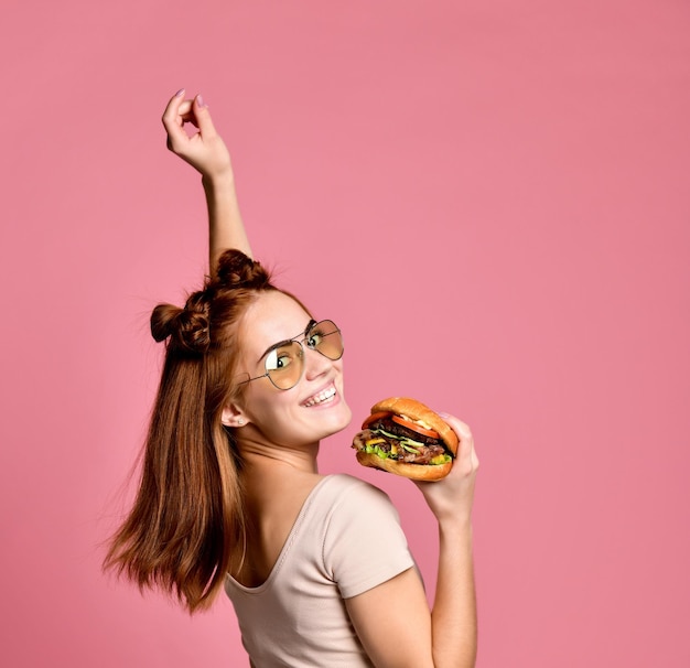 Horizontal studio shot of pretty young woman holding a burger