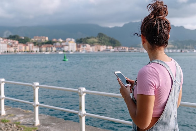 Horizontal view of unrecognizable woman using technology. Caucasian woman with smartphone on holidays in Asturias. Travel destination and technology concept.