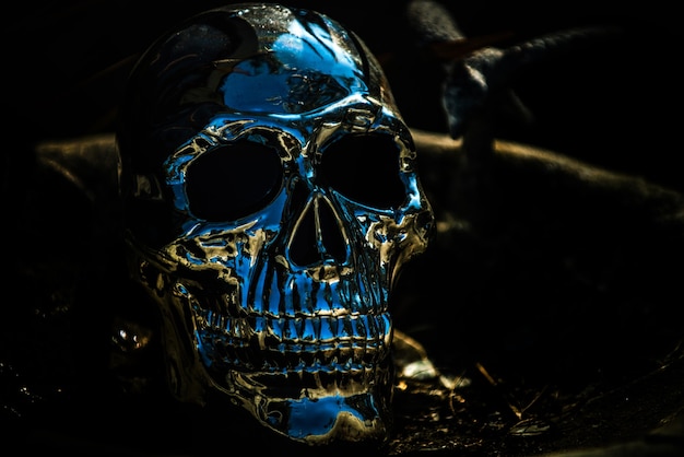 Horror Halloween background. Metallic human skull on black.