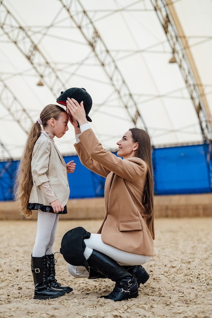 Horse lifestyle young kid with helmet Woman equiping young girl with helmet