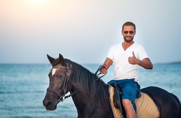 Horse riding on the beach at sunset