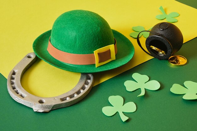 Horseshoe leprechaun hat coins cauldron and foamiran clover leaves on green background st patrick's day concept