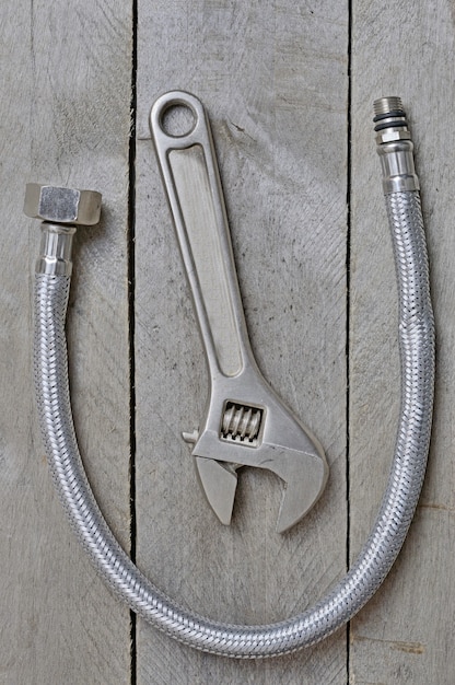 Hose and adjustable spanner on wooden table