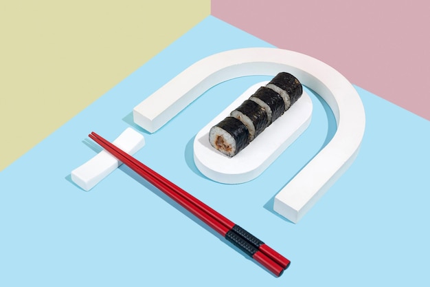 Hosomaki sushi rolls with eel on a white plaster stand on a colorful plain background blue pink yellow