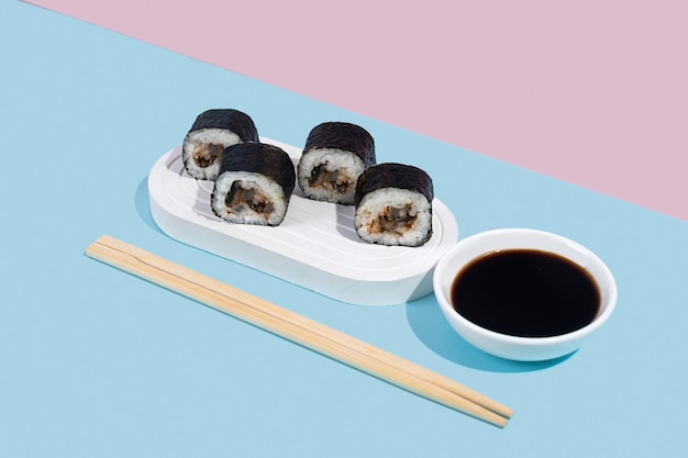 Hosomaki sushi with eel on a white stand on a colorful plain background blue pink