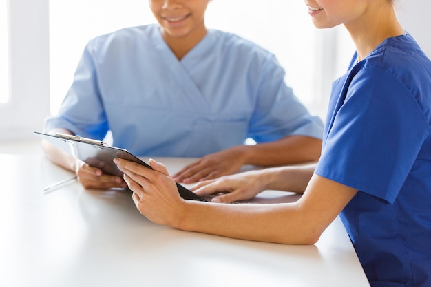 hospital, profession, people and medicine concept - close up of happy doctors with clipboard meeting at medical office