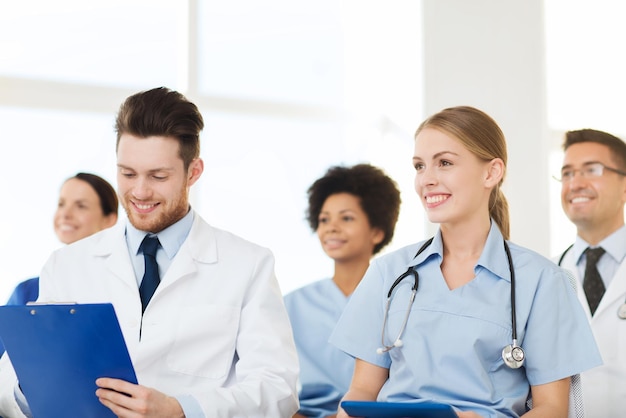 hospital, profession, people and medicine concept - group of happy doctors on seminar in lecture hall at hospital