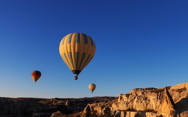 Hot air balloon rises very high in blue sky above white clouds bright sun shines