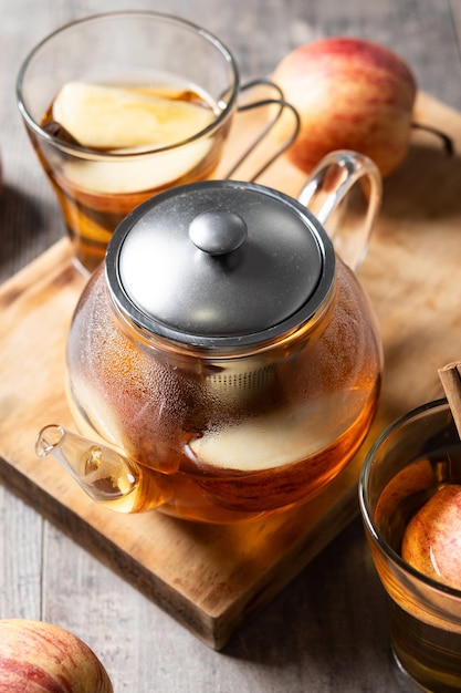 Hot apple drink with spices on wooden table