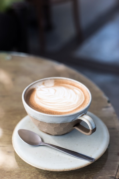 Hot art Latte Coffee in a cup and laptop on wooden table