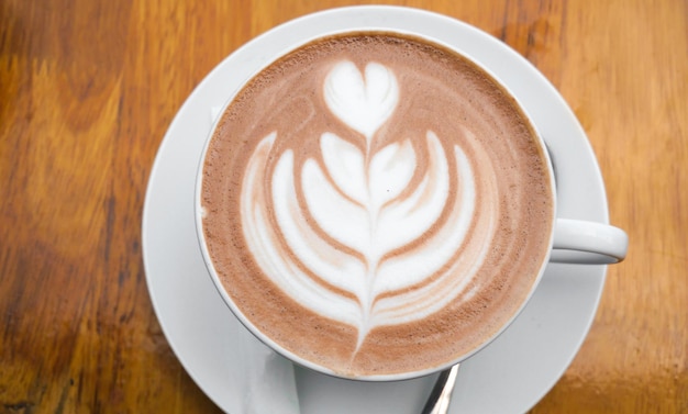 Hot art Latte Coffee in a cup on wooden table and Coffee shop blur background