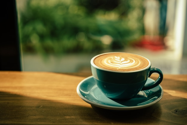 Hot art Latte Coffee in a cup on wooden table and morning light