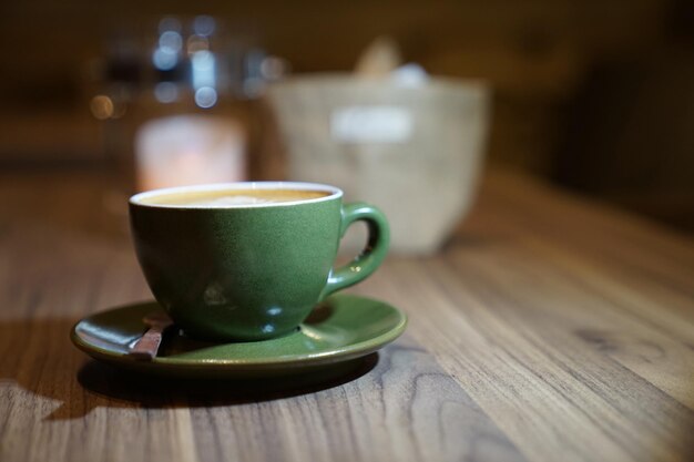 Hot Art Latte in the green cup on the wood table