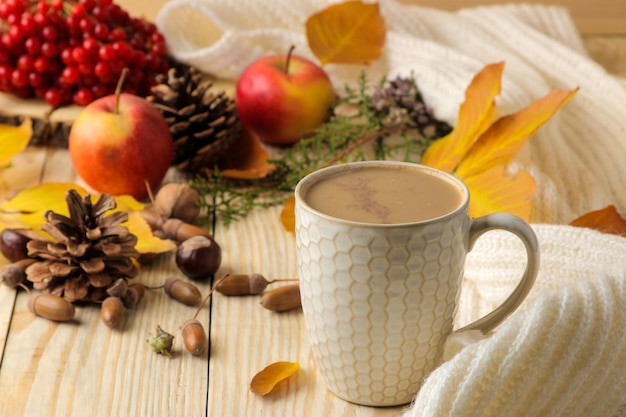 Hot autumn drink coffee or cocoa with yellow leaves and decorative pumpkins acorns and apples on a natural wooden table autumn composition