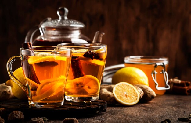 Hot black winter tea with ginger honey lemon and spice Immune booster drink in glass cup on rustic wooden table background copy space