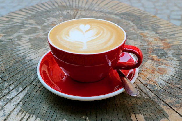 Hot Cappuccino Coffee in Red Cup Served on Tree Stump Table