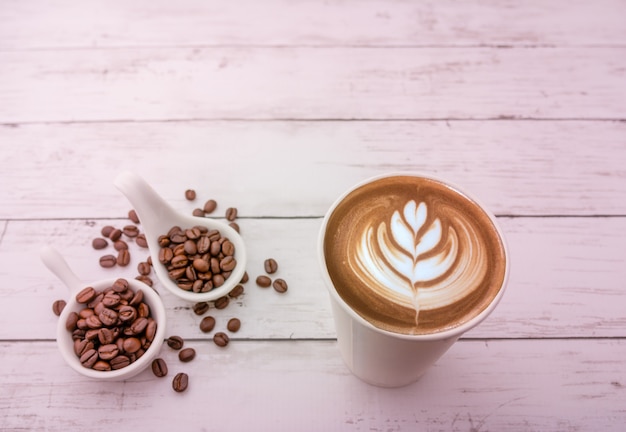 Hot cappuccino with roasted coffee beans on a wooden background and free space