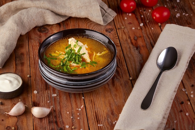 Hot chicken soup, wooden background