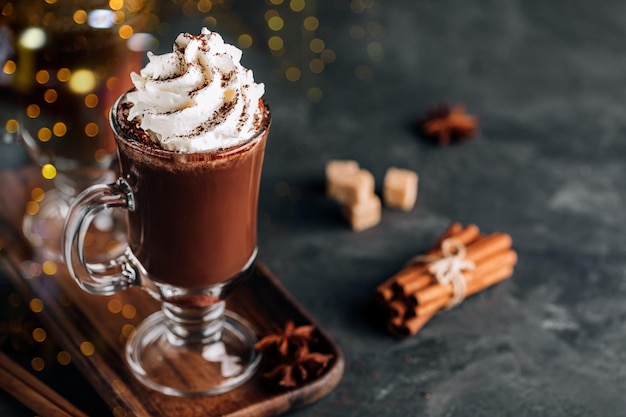 Hot chocolate cocoa with whipped cream in glass on dark background copy space Traditional drink for Christmas