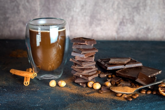 hot chocolate in a glass mug with cinnamon on the table and a chocolate bar with nuts