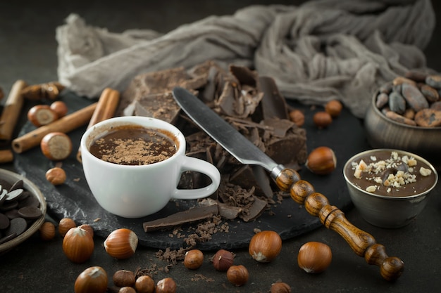 Hot chocolate on an old background in a composition with cocoa beans and nuts.