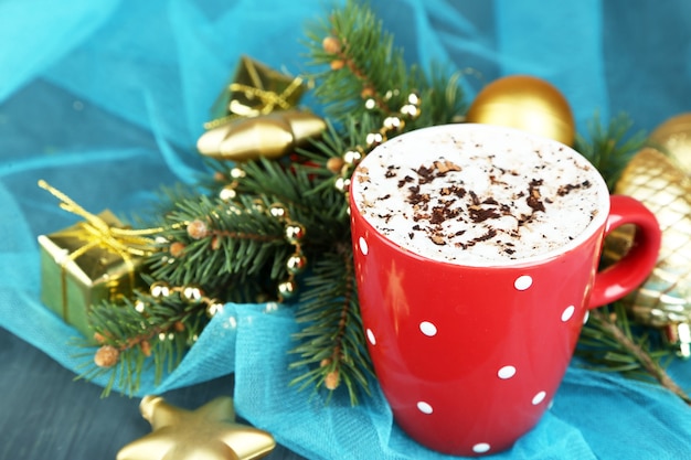 Hot chocolate with cream in color mug, on table, on Christmas decorations background