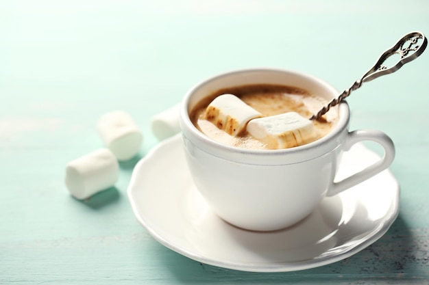 Hot chocolate with marshmallows in mug, on color wooden background