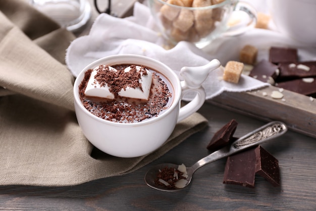 Hot chocolate with marshmallows in mug, on tray, on color wooden background