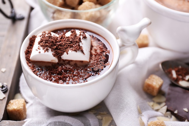 Hot chocolate with marshmallows in mug, on tray on wooden table