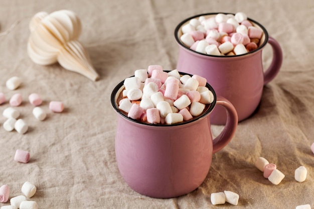 Photo hot chocolate with marshmallows in mugs on a linen tablecloth with christmas toy