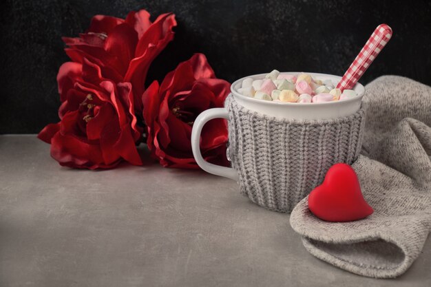 Hot chocolate with marshmallows, red heart on the cup on the table