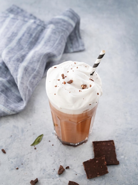 Hot chocolate with whipped cream in a tall glass on a blue background Top view