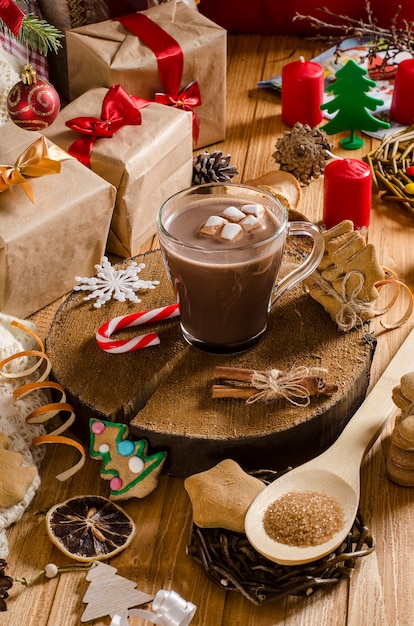 Hot Christmas and New Year's drink of cocoa with marshmallows on a table with gifts, Christmas cookies and Christmas tree branches. Hot chocolate.