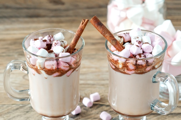 Hot cocoa or chocolate drink with marshmallow in glass mug on wooden table. Concept of cosy Christmas and New Year holidays, copy space.