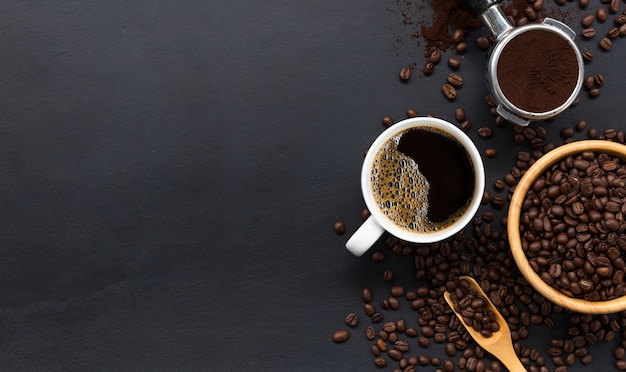 Hot coffee and bean on black wooden table background. top view