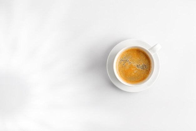 Hot coffee cup mug of cappuccino latte in hard light on white background with shadow top view